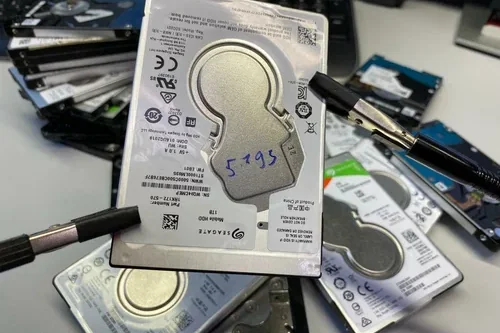 Stapel ausgebauter 2,5-Zoll-Festplatten von Seagate mit Werkzeug auf dem Labortisch